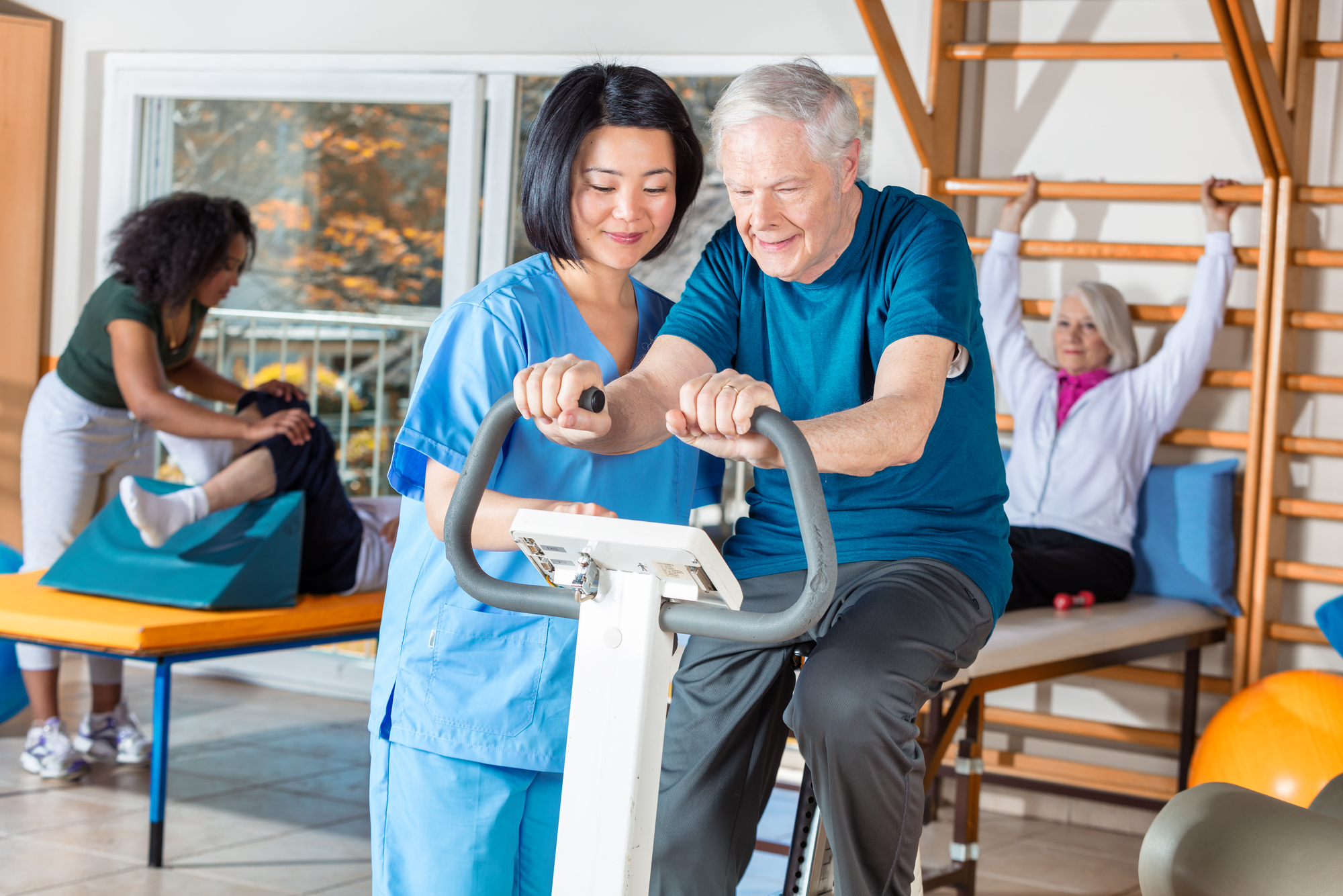 Asian nurse helping elder man in hospital gym
