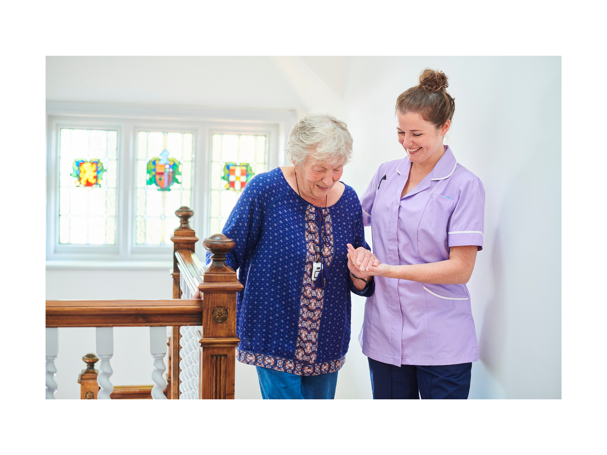 Health care worker assists an elderly woman down the stairs, fostering companionship and support in a well-lit environment with stained glass windows.